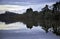 Dark shadowy trees and clouds reflected in the still waters of a lake