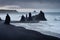 Dark sharp rocks protrude from water on iceland beach