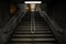 Dark shot of a concrete staircase with a middle handrail in a public subway station