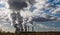 Dark side of steam clouds and smoke of cooling towers and chimneys of a brown coal power plant against the bright sky