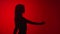 Dark silhouette of cheerful dancing lady having fun isolated red studio. Medium shot on RED camera