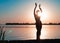 Dark silhouette of dancing slim woman near big river