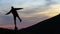 Dark silhouette of a hiker balancing on a stone in evening mountains.