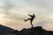 Dark silhouette of a hiker balancing on a summit stone in evening mountains