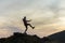 Dark silhouette of a hiker balancing on a summit stone in evening mountains