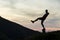 Dark silhouette of a hiker balancing on a summit stone in evening mountains