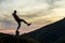 Dark silhouette of a hiker balancing on a summit stone in evening mountains