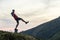 Dark silhouette of a hiker balancing on a summit stone in evening mountains