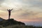 Dark silhouette of a hiker climbing a mountain at sunset raising his hands standing on summit like a winner