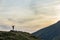 Dark silhouette of a hiker climbing a mountain at sunset raising his hands standing on summit like a winner