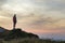 Dark silhouette of a hiker on a mountain at sunset standing on summit like a winner