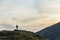 Dark silhouette of a hiker on a mountain at sunset standing on summit like a winner