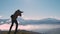 Dark silhouette of a hiker photographer taking picture of morning landscape in autumn mountains.