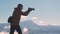 Dark silhouette of a hiker photographer taking picture of morning landscape in autumn mountains.