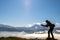 Dark silhouette of a hiker photographer taking picture of morning landscape in autumn mountains