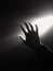 dark silhouette of human male hand with fingers in spotlight or backlight light with gesture on black background with dramatic