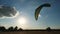 Dark silhouette of a man in a special suit, trains in the control and handling of a paraglider on the ground, at sunset