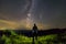 Dark silhouette of a man standing in mountains at night enjoying milky way and Neowise comet with light tail in dark sky view