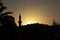 Dark silhouette of a mosque with a tall minaret at sunset.