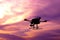 Dark silhouette of self-assembled drone hovering in a colorful s