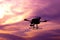 Dark silhouette of self-assembled drone hovering in a colorful s