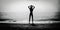 Dark silhouette of slim girl on the sea beach with hands by head, bw photo