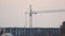 Dark silhouette of tower crane and small silhouettes of workers at high residential apartment building construction site