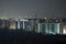 Dark silhouette of tower cranes at high residential apartment buildings construction site at night. Real estate