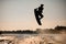 dark silhouette of wakeboarder athlete man jumping high making tricks in the air