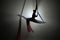 Dark silhouette of a young woman equilibrist demonstrating twine, hovering on an airy silk at height. An acrobat