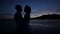 Dark silhouettes of the bride and groom on a tropical ocean beach at sunset. Sensual hugs and kisses.