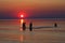 Dark silhouettes of young people playing in the sea during sunset