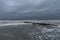 Dark skies and rough surf with an abundance of sea foam along a metal erosion control wall, South Carolina coast