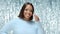 Dark skin brunette attractive girl in a light blue sweater on a shiny glitter background. High quality video footage.