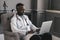 Dark-skinned doctor talking on Skype zoom with a laptop