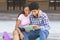 Dark-skinned teens watching video on digital tablet sitting outdoors