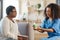 Dark-skinned woman with short hair talking to nurse bringing pills