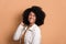 Dark skinned woman touching hair wearing white jacket in studio shot. portrait, real people concept