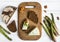 Dark sliced bread, blue cheese with nuts on wooden cutting board decorated with asparagus. Flat lay, top view