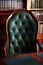 Dark solid interior of old library with books on the wooden shelves. Vintage classic chair green leather and red wood, antique tab