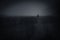 Dark spooky landscape with lonely man walking on field