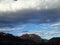 Dark storm clouds looming with blue skies and clouds behind the mountains