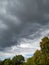 dark storm clouds swirl over the trees in the city center. Clouds in the sky.