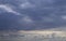 Dark stormy blue sky above with small white light clouds below. Natural cloudscape background