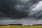 Dark stormy clouds over corn field at summer