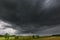 Dark stormy clouds over corn field at summer