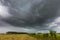 Dark stormy clouds over corn field at summer