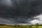 Dark stormy clouds over corn field at summer