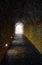 Dark tunnel made of natural stones with light at the end