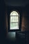 Dark vintage staircase interior in old building, stair with wooden railing, big window with day light